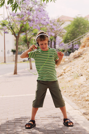 Cute autistic boy with headphones dancing in the streetの写真素材