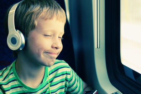 Portrait of cute boy with headphones traveling in the trainの写真素材