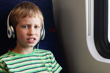 Portrait of cute boy with headphones traveling in the trainの写真素材