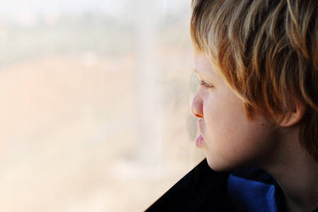 Cute 7 years old boy looking through the window in the trainの写真素材