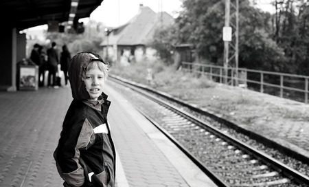 7 years old boy standing on a railway station and waiting for the trainの写真素材