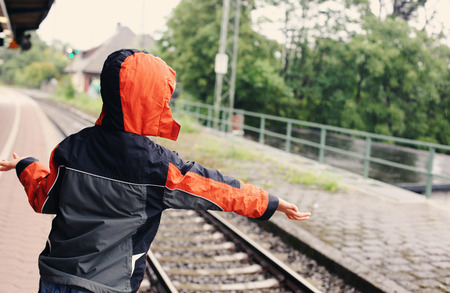 7 years old boy standing on a railway station and waiting for the trainの写真素材