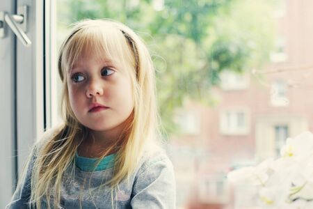 Portrait of 5 years old girl lsitting near the windowの写真素材