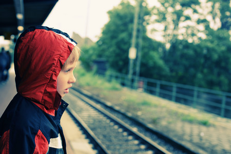 7 years old boy standing on a railway station and waiting for the train