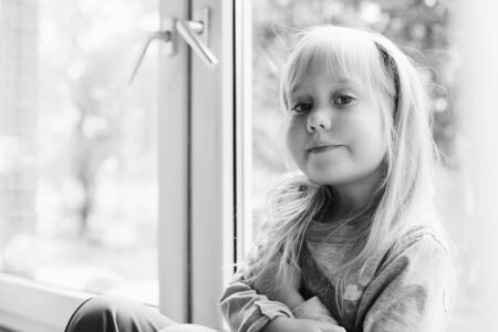 Portrait of 5 years old girl lsitting near the window