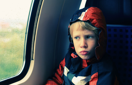 7 years old boy sitting in the train and looking to the rainの写真素材