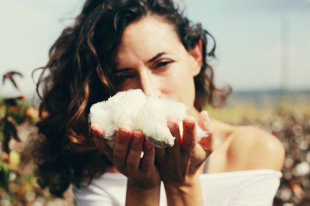 beautiful woman holding natural cotton. Focus on the armsの写真素材