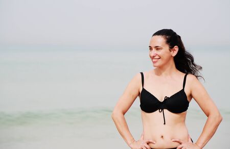 beautiful 35 years old woman standing on the shore of the beachの写真素材