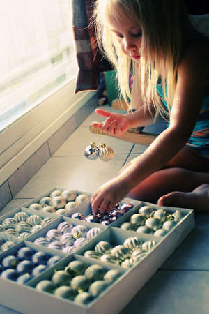 sweet little girl is playing with christmas ballsの写真素材