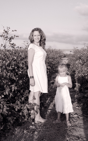 happy mother with daughter standing on a cotton field in sunset colorsの写真素材