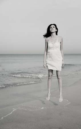 beautiful 35 years old woman standing on the shore of the beachの写真素材
