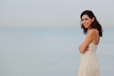 beautiful 35 years old woman standing on the shore of the beachの写真素材