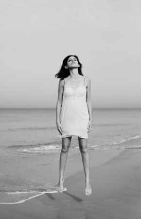 beautiful woman standing on the shore of the beachの写真素材