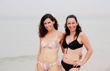 two beautiful 35 years old women standing on the beachの写真素材
