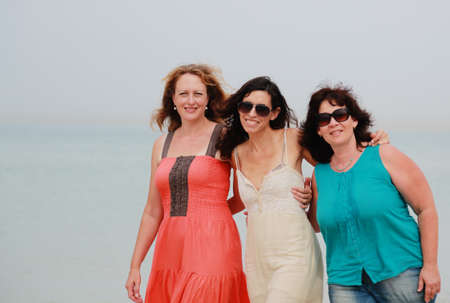 Three best friends walking at seasideの写真素材