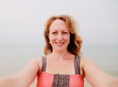 beautiful 35 years old woman standing on the shore of the beach. selfieの写真素材