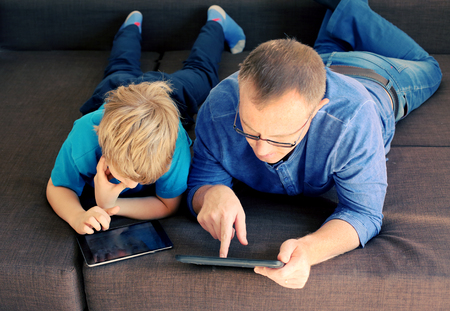 father and son playing games on tabletsの写真素材