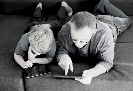 father and son playing games on tabletsの写真素材
