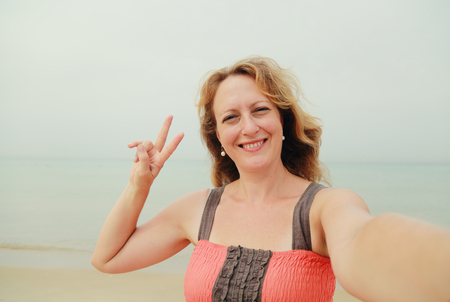 beautiful 35 years old woman standing on the shore of the beach. selfieの写真素材