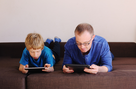 father and son playing games on tabletsの写真素材
