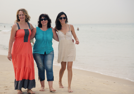 Three best friends walking at seasideの写真素材
