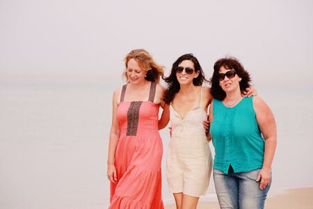 Three best friends walking at seasideの写真素材