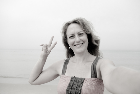 beautiful 35 years old woman standing on the shore of the beach. selfieの写真素材