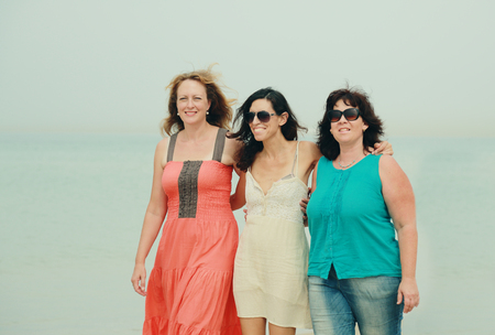 Three best friends walking at seasideの写真素材