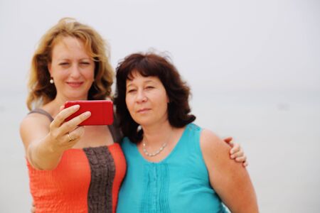 two best friends making selfie photo. focus on the arm holding smartphoneの写真素材