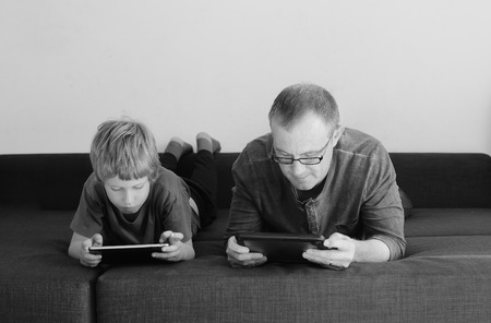 father and son playing games on tabletsの写真素材