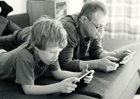 father and son playing games on tabletsの写真素材