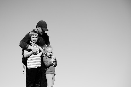 father standing with two kids on blue sky backgroundの写真素材