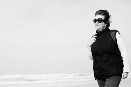 Senior woman walking on the winter beachの写真素材