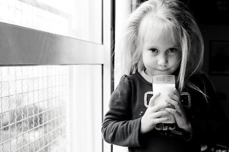 5 years old girl holding glass of milkの写真素材