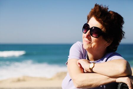 Portrait of happy senior woman sitting neat the seaの写真素材