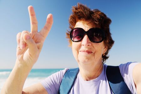 Selfie portait of happy senior woman on the beachの写真素材