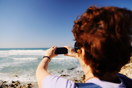 Senior woman making photo of the seaの写真素材