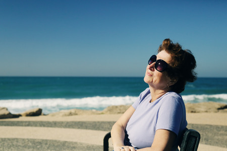 Portrait of happy senior woman sitting neat the seaの写真素材