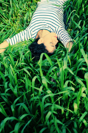 Young beautiful woman lying on green grassの写真素材