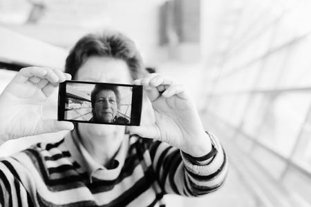 Senior woman taking selfy picture on mobile deviceの写真素材