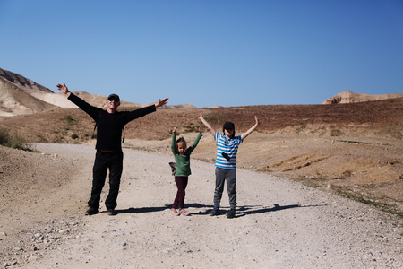 father hiking with two kids in the desertの写真素材