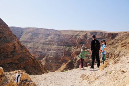 father hiking with two kids in the desertの写真素材
