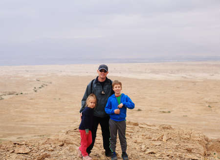 father hiking with two kids in the desertの写真素材