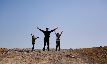 father hiking with two kids in the desertの写真素材