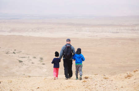 father hiking with two kids in the desertの写真素材