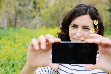 Outdoors portrait of beautiful 40 years old woman holding mobale deviceの写真素材