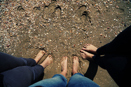 Three women standing on the brown sandy beachの写真素材