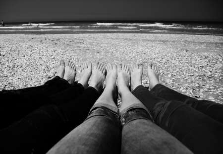 Four women sitting on the brown sandy beachの写真素材