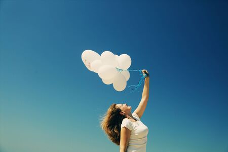Beautiful redhead woman holding white balloonsの写真素材