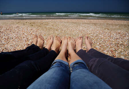 Four women sitting on the brown sandy beachの写真素材